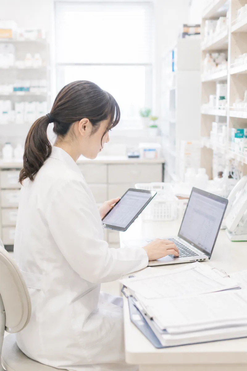 タブレットとPCで事務作業をする薬剤師